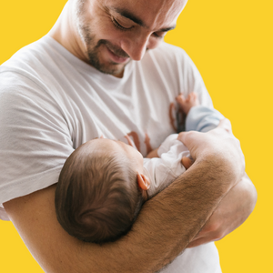 Man in white t-shirt holding baby in arms with head supported