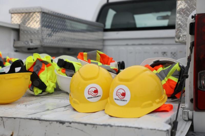 Yellow hard hats with Mesa County logos sit in white truck.