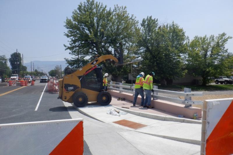 Two construction workers next to orange large equipment. 