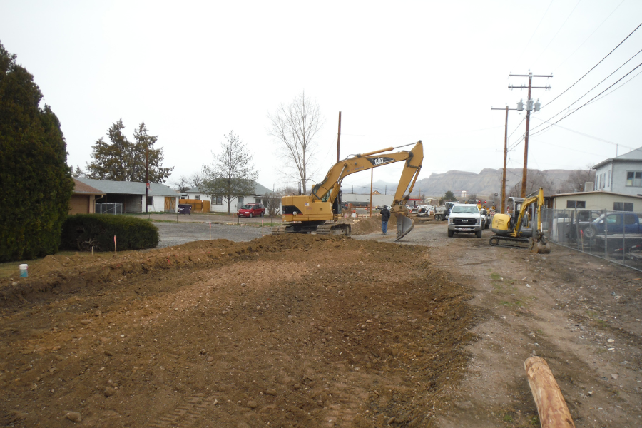 Excavation equipment in progress of excavating medium brown dirt on gloomy day.