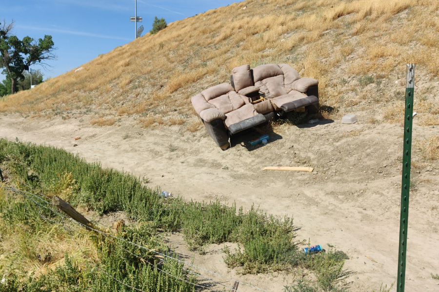 Tan couch sits on open land.