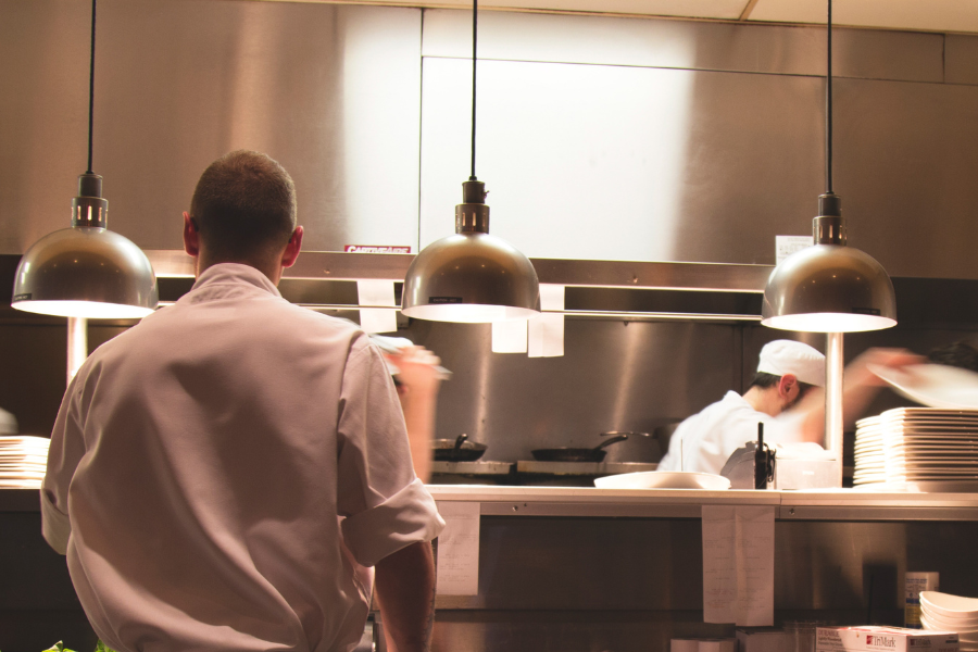 Two employees wearing white uniforms working in a restaurant's kitchen.