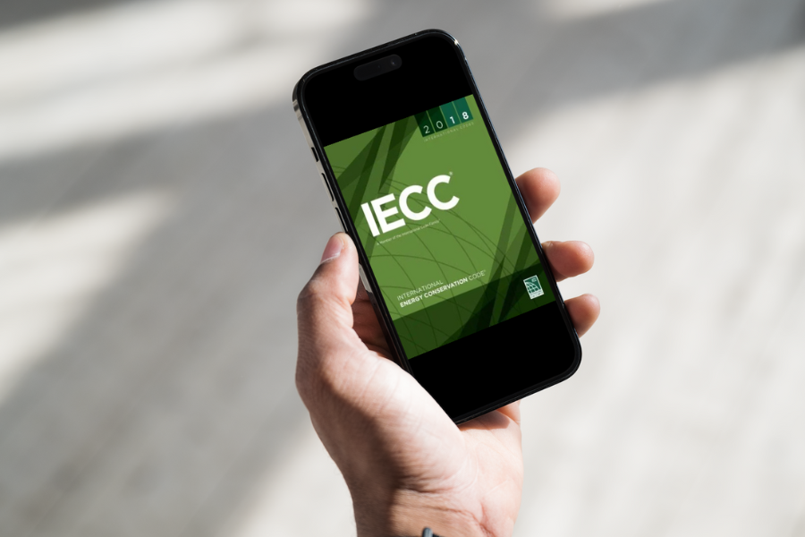 Hand holding smart phone with green background reading "IECC".
