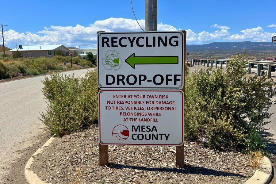 Sign outside Mesa County Landfill reading "Recycle drop-off" with green arrow pointing left. 