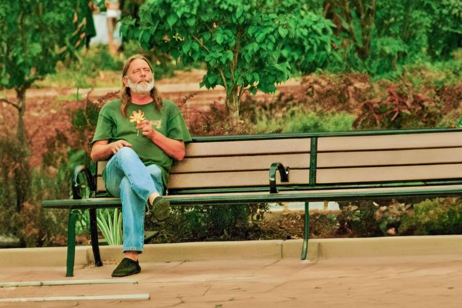Bruce Lohmiller sits on bench holding orange leaf.