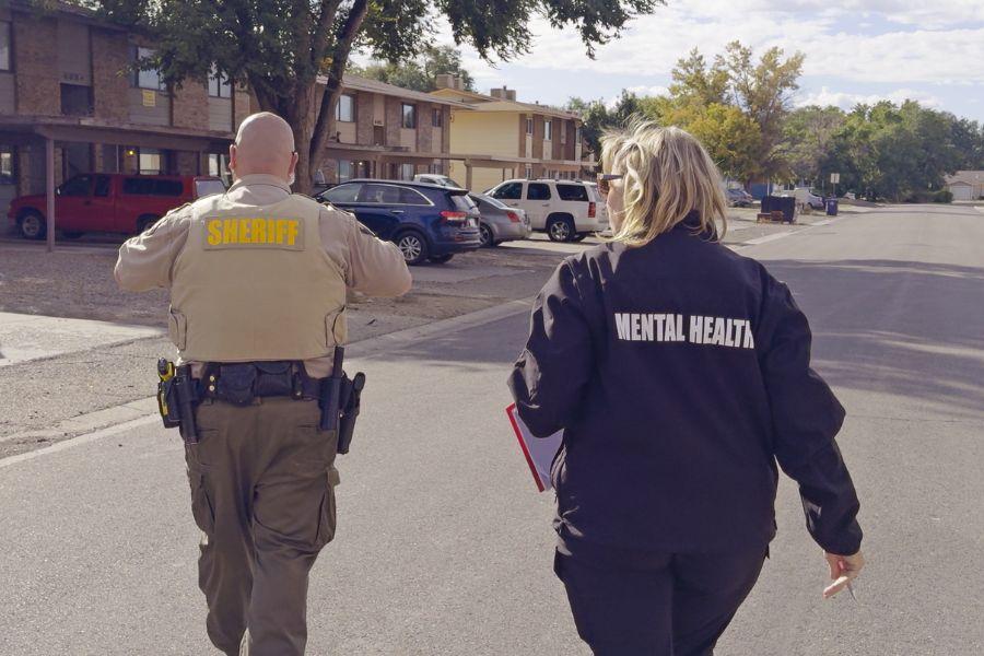 A sheriff deputy and a clinician walk together as they respond to a call