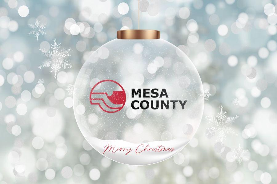 Clear Christmas ornament with Mesa County logo and red font reading "Merry Christmas."