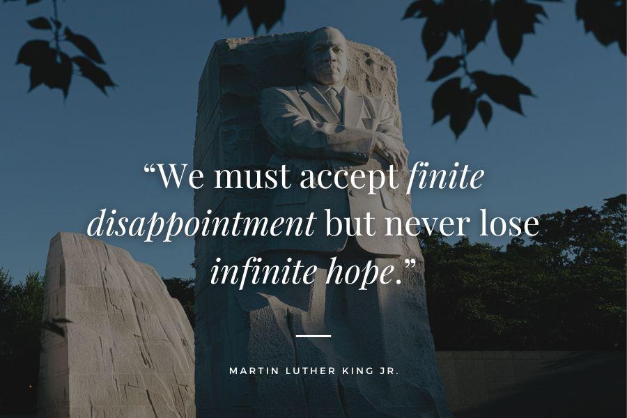 Statue of Martin Luther King Jr. with white text reading "We must accept finite disappointment but never lose infinite hope".