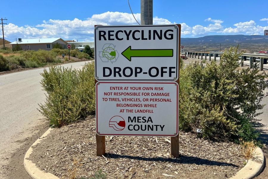 Mesa County sign reading, "Recycling drop off," in green text with a green arrow pointing left. 