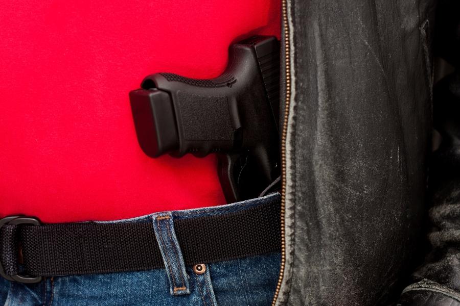 Gun tucked under jeans with red shirt and black jacket. 